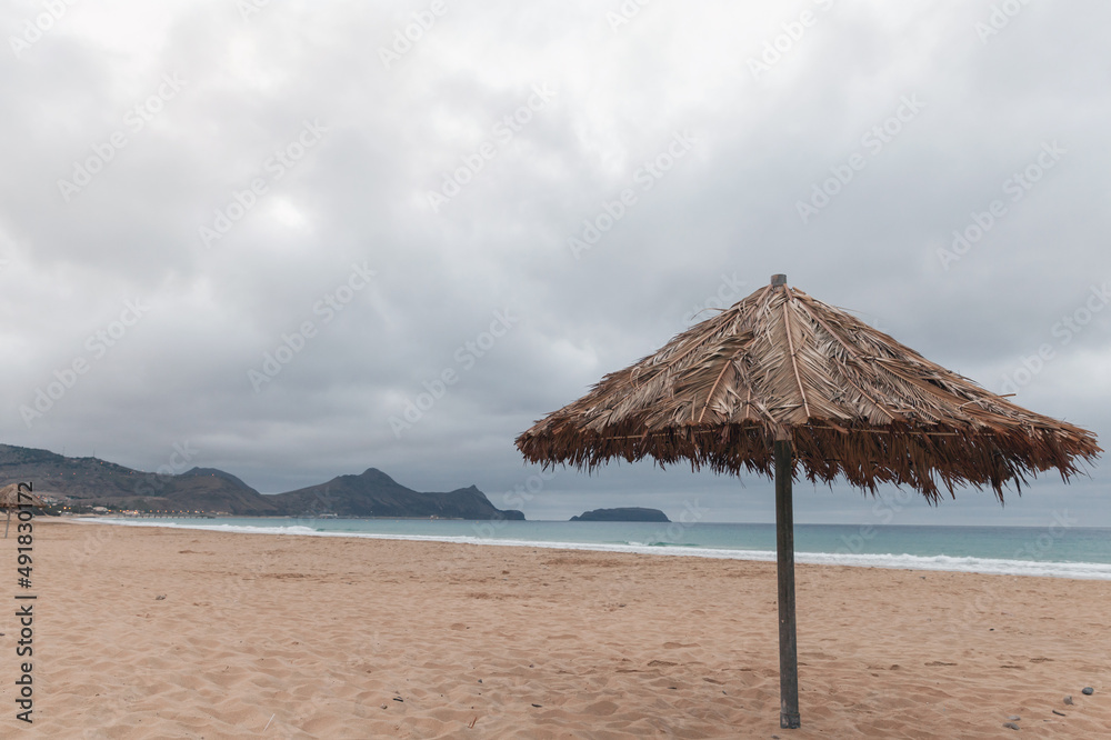 Wooden umbrella is on an empty beach