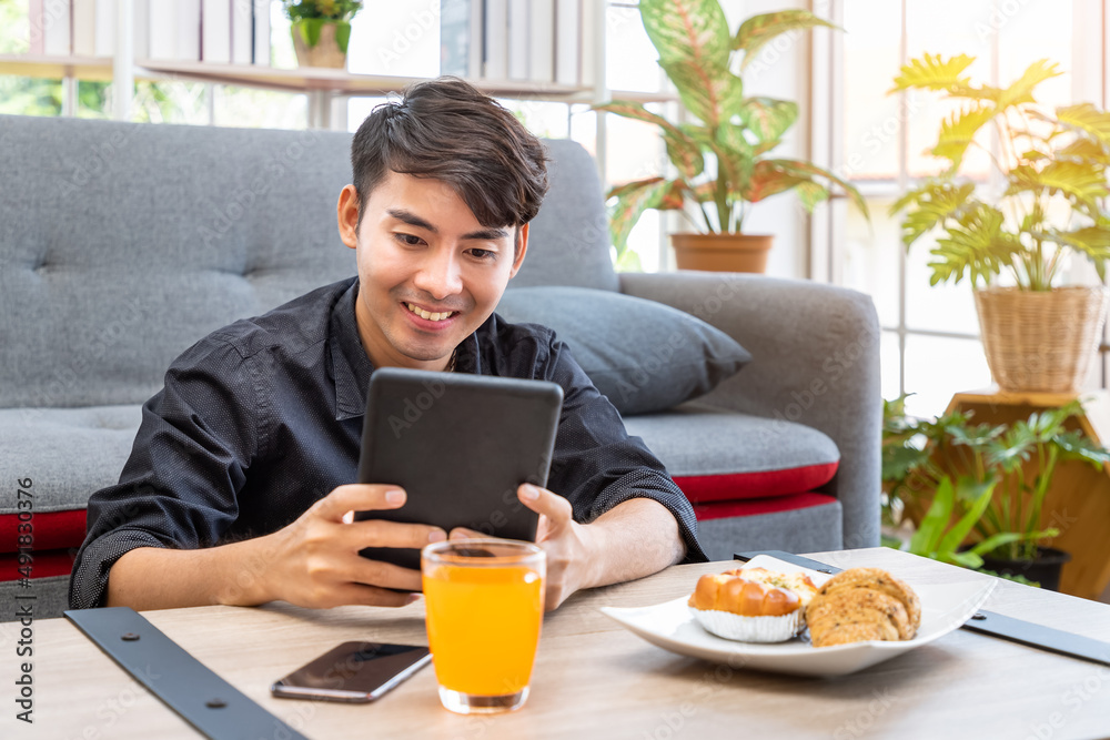 Asian businessman freelance sitting on floor front of sofa using table with meal breakfast. Concept for working at home. Asian businessman freelance sitting on floor front of sofa using table with meal breakfast. Concept for working at home.