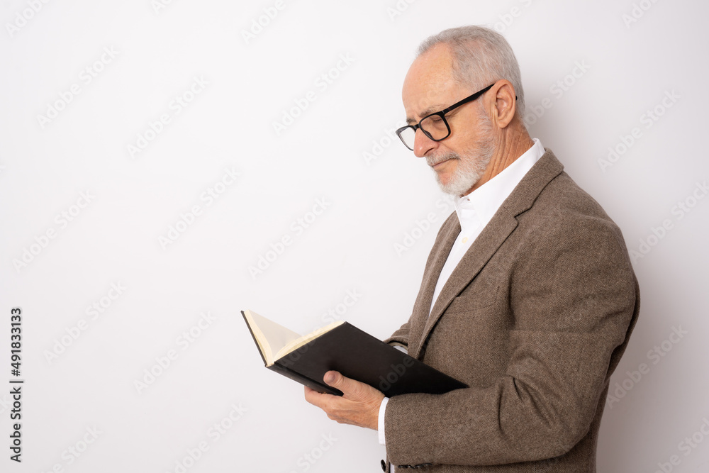 Portrait of senior man in elegant clothing reading a book standing isolated over white background. Portrait of senior man in elegant clothing reading a book standing isolated over white background.