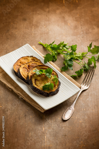 fried eggplants with parsley over wooden table