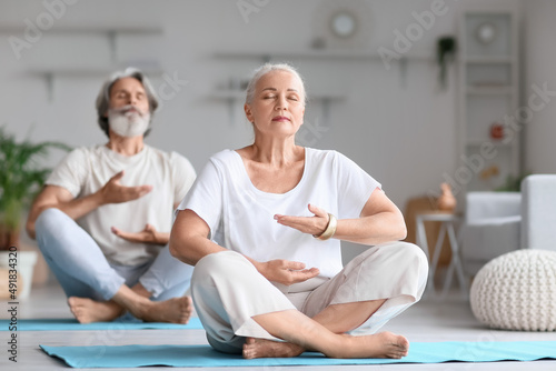 Mature couple practicing yoga at home
