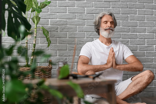 Mature man meditating at home