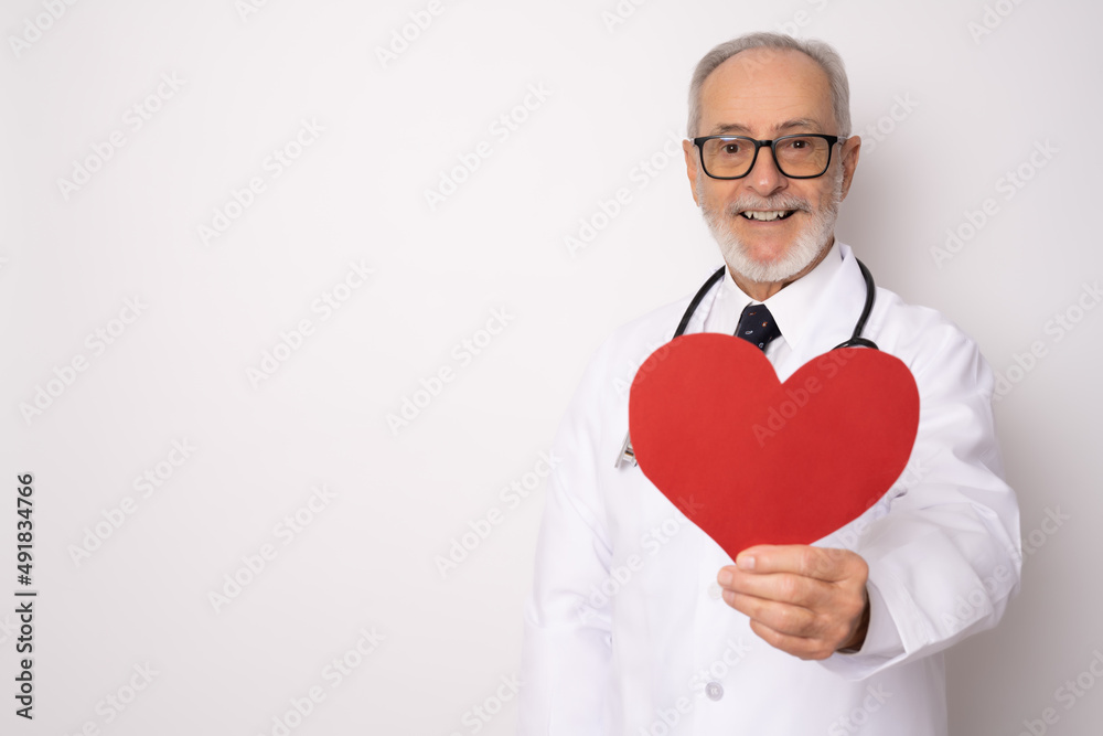 Senior age handsome grey-haired doctor man holding heart of red paper with a happy face standing and smiling with a confident smile showing teeth. Medical concept. Senior age handsome grey-haired doctor man holding heart of red paper with a happy face standing and smiling with a confident smile showing teeth. Medical concept.