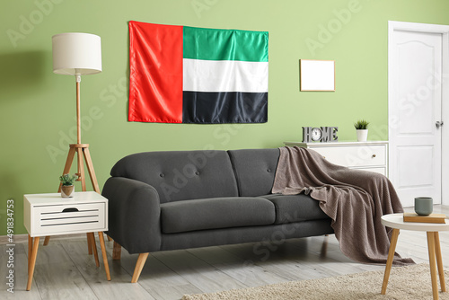 Canvas Print Interior of stylish living room with black sofa, UAE flag and green wall