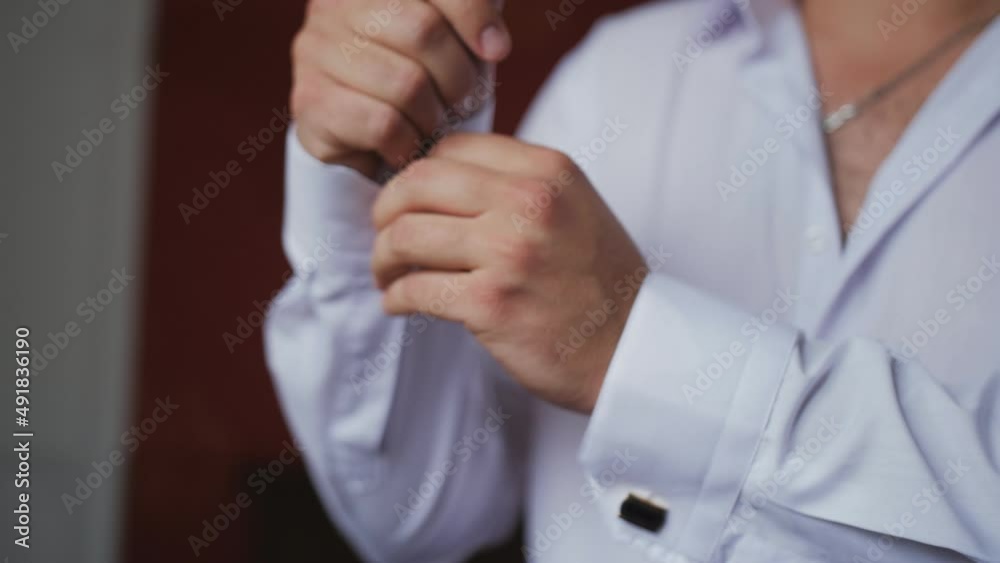 A businessman man fastens the cuffs on his shirt. Office plankton is going to work. A businessman man fastens the cuffs on his shirt. Office plankton is going to work.