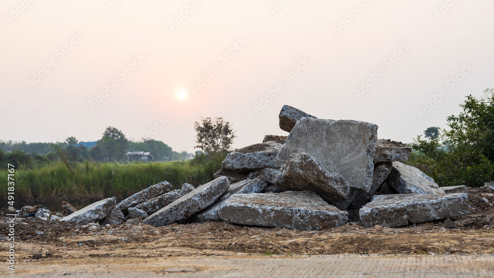 A close-up view of large concrete rubble piled up on the ground from a country road demolition.