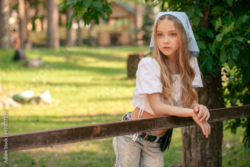 Teenage girl leaning on fence of animal stall in country estate in summer photo