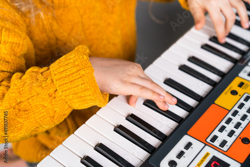 a little girl playing the synthesizer  the concept of teaching children music  hands close-up