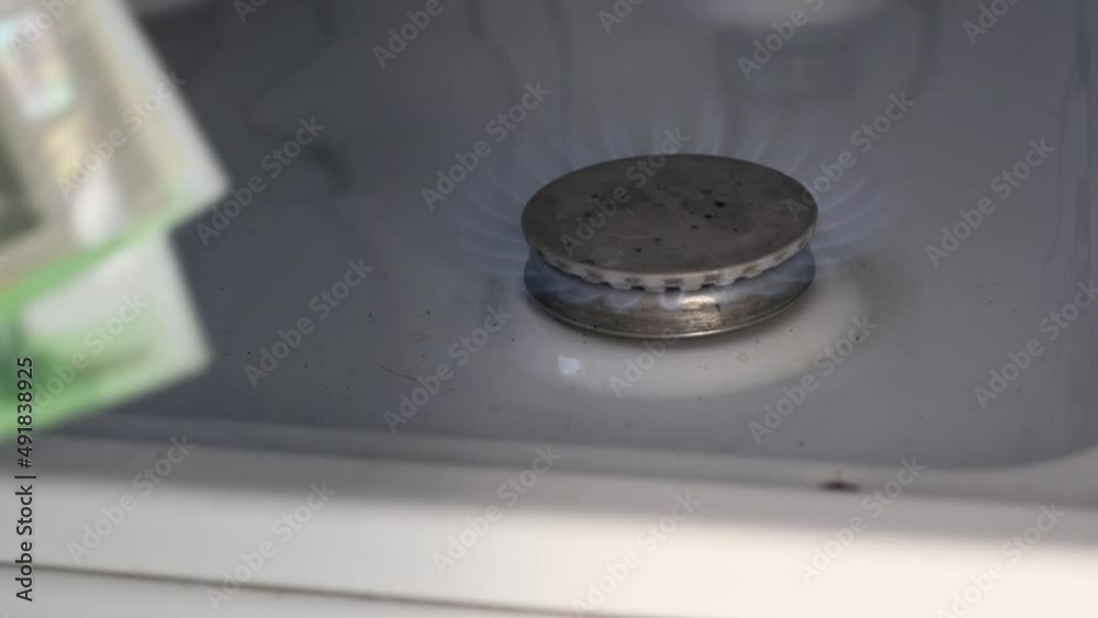 man counting a pack of euro currency cash banknotes close-up near a burning gas stove. concept of rising price of hydrocarbons man counting a pack of euro currency cash banknotes close-up near a burning gas stove. concept of rising price of hydrocarbons