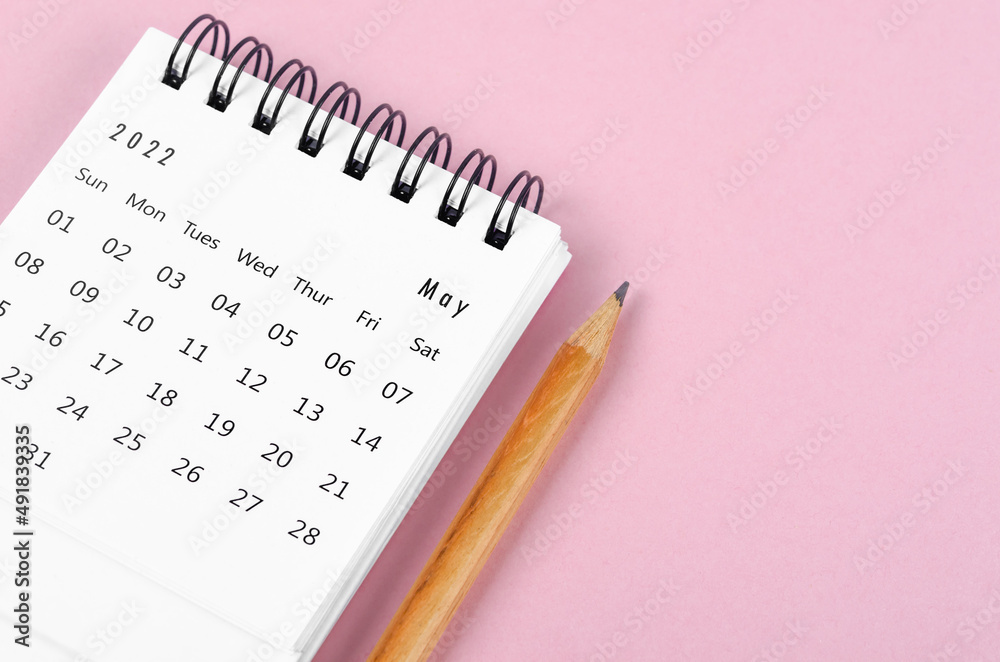 May 2022 desk calendar with wooden pencil on pink background. May 2022 desk calendar with wooden pencil on pink background.