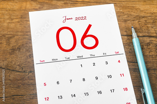 June 2022 calendar with pen on wooden table. photo