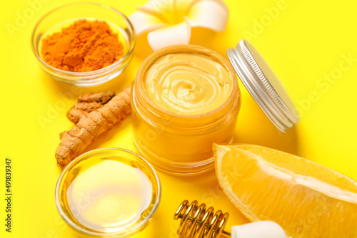 Composition with ingredients for turmeric mask and flowers on yellow background, closeup