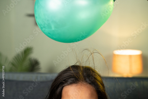 close up shoto of kids playing by placing balloon to attracting hair - conept of static cling home science experiment and learning. photo