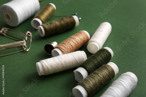 Thread spools with pins on green background, closeup