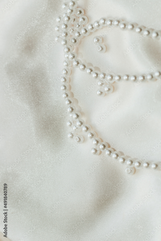 Pearl bijouterie beads on silk texture background.