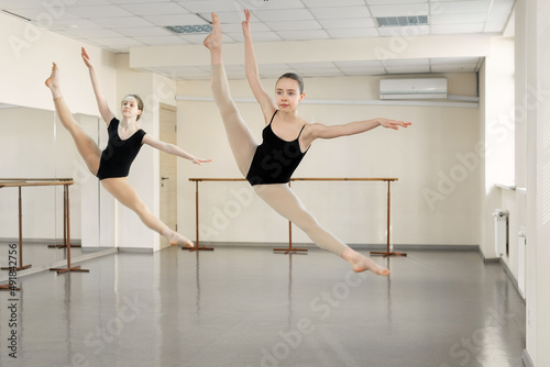 Young girls dancing ballet in studio. Choreographed dance by a group of graceful pretty young ballerinas practicing during class before performance. Classical dance school