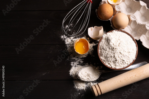 Ingredients for pastries: flour, eggs on a dark background. Space for text. Top view.