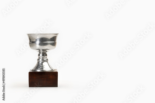 Trofeo de acero de latón en forma de copa plateada con base de madera sobre un fondo blanco liso y aislado. Vista de frente y de cerca. Copy space