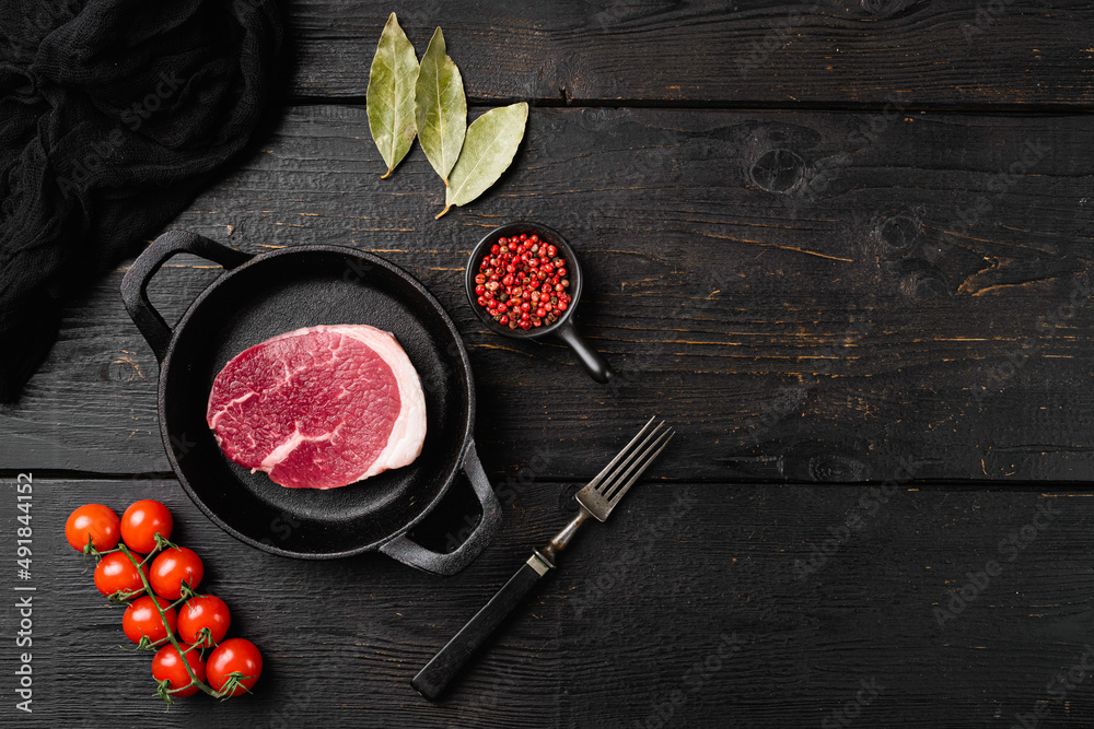 Raw beef steak, on black wooden table background, top view flat lay, with copy space for text
