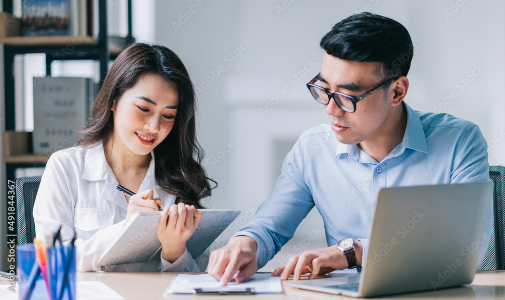© Timeimage - Two Asian businesspeople working at office