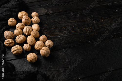 Walnuts with shells, on black wooden table background, with copy space for text