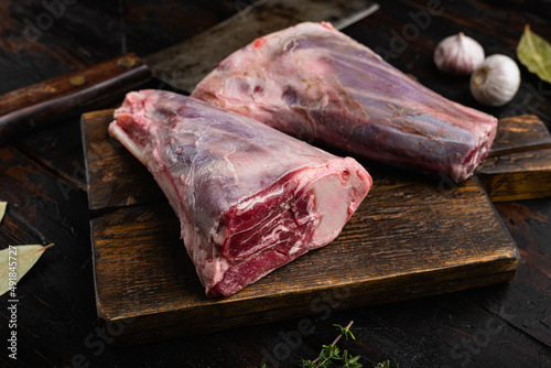 Raw lamb shanks with ingredients, on old dark  wooden table background photo