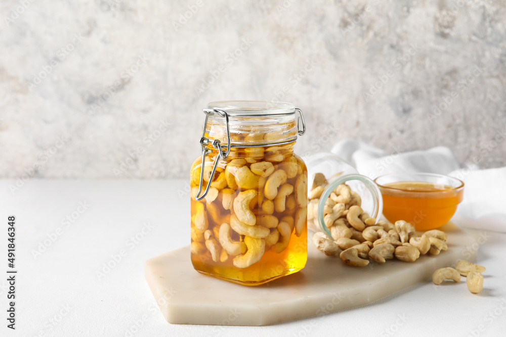 Board with jar of sweet cashew nuts in honey on grunge background Board with jar of sweet cashew nuts in honey on grunge background