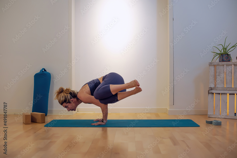 side crow pose yoga position - woman performing Parsva Bakasana pose indoors