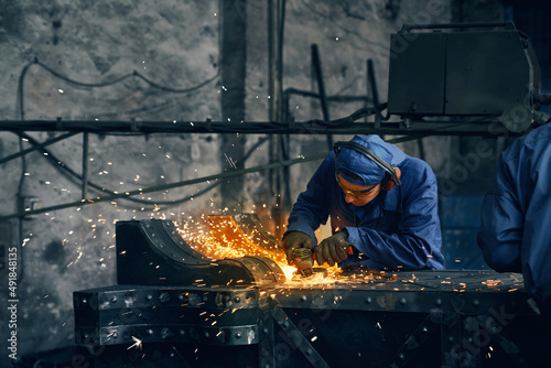 Obraz na płótnie Close up of man in special dark blue uniform making gates from iron in garage or workshop