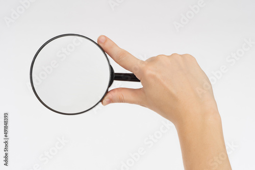 Magnifying glass in hand. Magnifying glass as symbol of search and research. Hand with magnifying glass on light background. Zoom tool. View items under magnification. Hand with loupe for your design