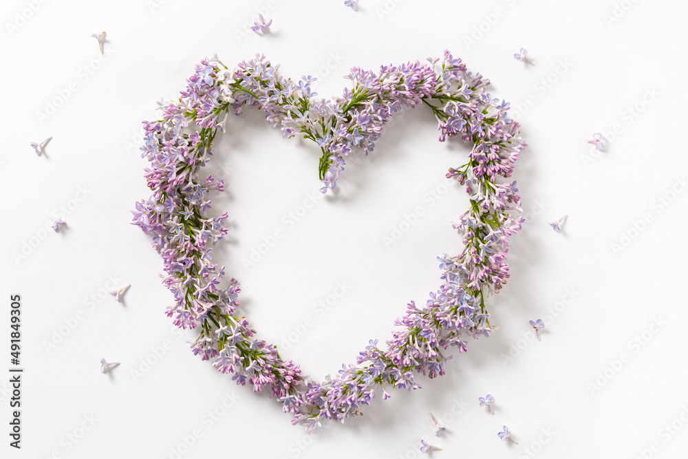Beautiful lilac flowers in heart shape on a white background. Springtime background, floral design. Love spring. Flat lay. Creative floral background. Greeting card, poster, print