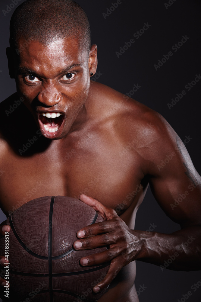 Fototapeta premium I challenge you. Studio portrait of a determined young basketball player standing against a black background.