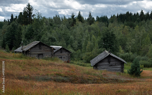 wooden bathhouses and sheds by the river against the backdrop of the northern forest