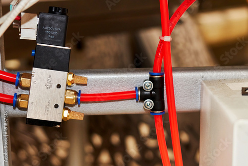 orange duct tubes of pneumatic system connected to solenoid electric valve photo