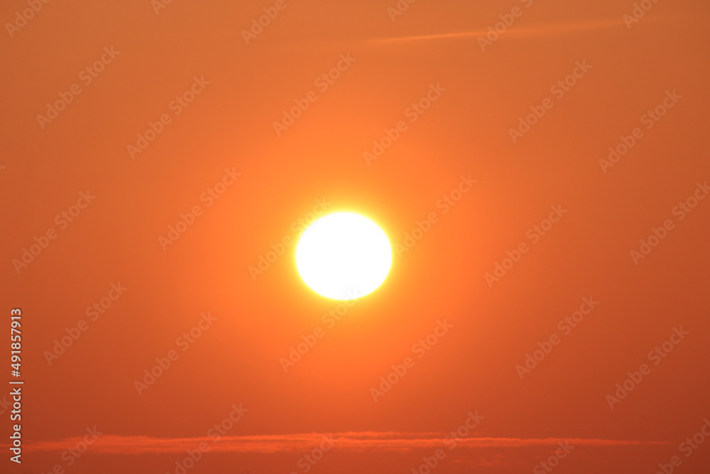Sun disk at sunset and thin stripes of clouds horizontal photo