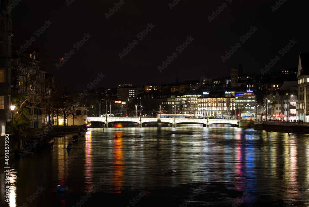 Cityscape of the old medieval old town of Zürich on a dark winter night with river Limmat in the foreground and beautiful reflections in water. Photo taken February 24th, 2022, Zurich, Switzerland.