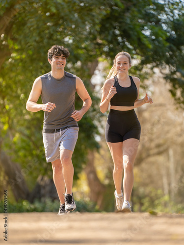 Young couple doing sports running on a park path and smiling