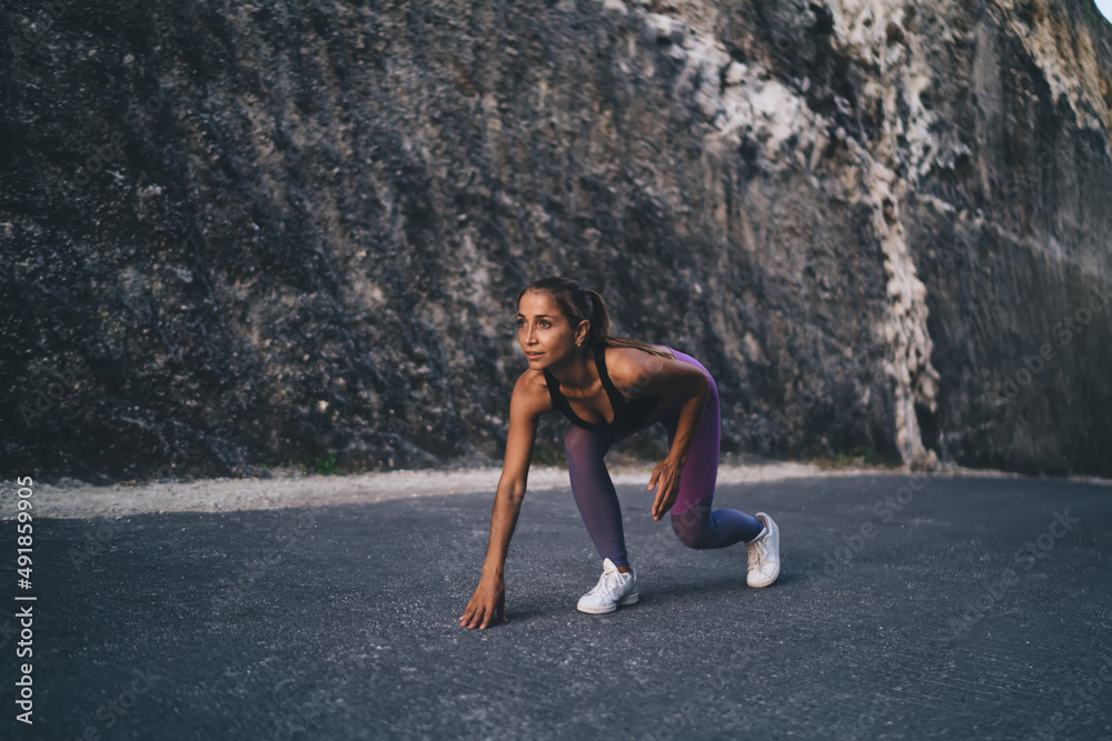 Fototapeta premium Pumped up jogger in sportswear ready for sprinting during morning cardio training - pursuit challenge, Caucasian female athlete feeling motivation for speed running - workout endurance concept
