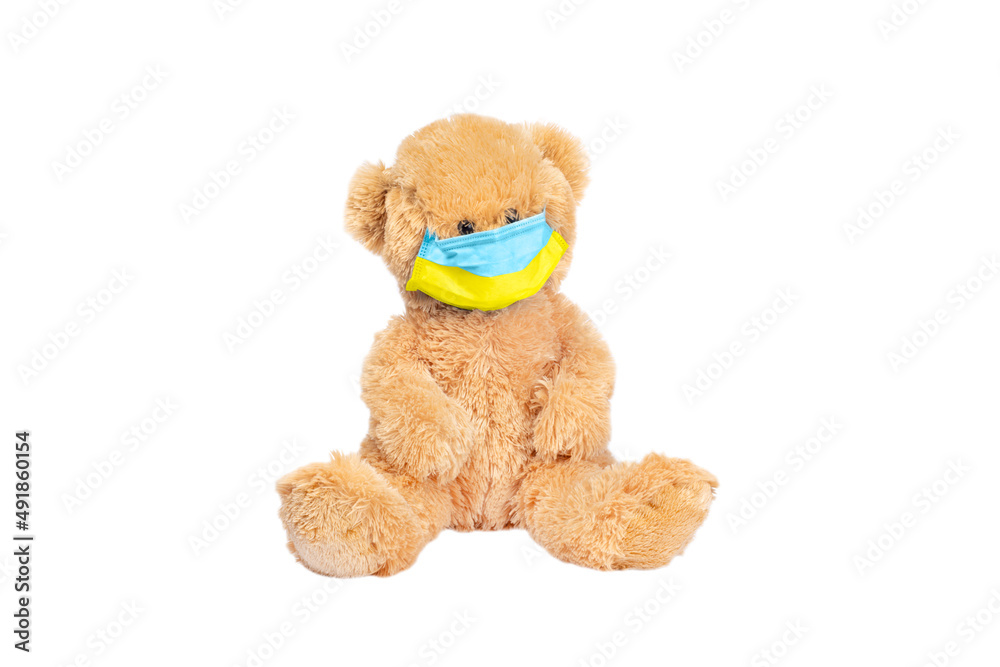 Teddy bear wears PP non-woven disposable medical face mask toned in yellow and blue colors of Ukrainian flag isolated on white background. Stop Coronavirus and Air pollution concept. Copy space Teddy bear wears PP non-woven disposable medical face mask toned in yellow and blue colors of Ukrainian flag isolated on white background. Stop Coronavirus and Air pollution concept. Copy space