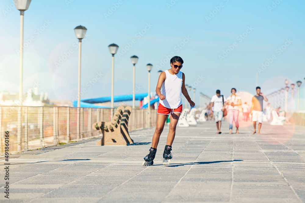 Obraz premium Staying fit and having fun. Shot of an attractive young woman rollerblading on a boardwalk.
