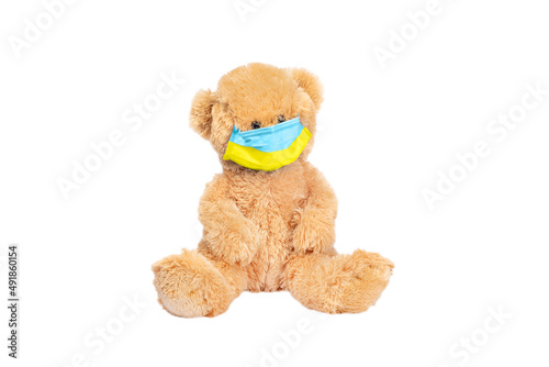 Teddy bear wears PP non-woven disposable medical face mask toned in yellow and blue colors of Ukrainian flag isolated on white background. Stop Coronavirus and Air pollution concept. Copy space photo