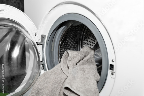 Unloading out the laundry from the washing machine. Loading clothes in a washing machine
