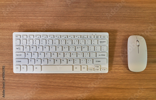 White wireless keyboard and mouse on wood table background