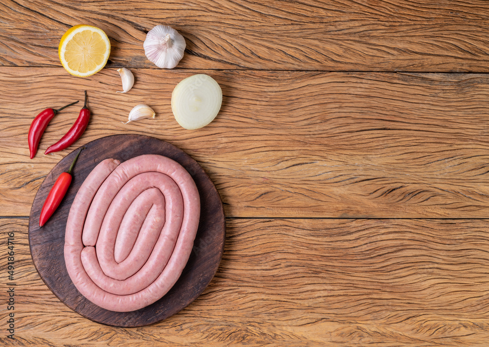Raw pork sausage on a wooden board with silician lemon, seasonings and copy space Raw pork sausage on a wooden board with silician lemon, seasonings and copy space