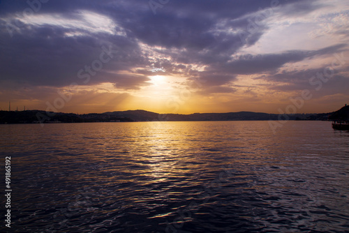 amazing colorful clouds on sunset. Beautiful golden sunset in the sea with saturated sky and clouds. Reflection in the water. Rocky coastal line. Peaceful serene landscape. Nature background.