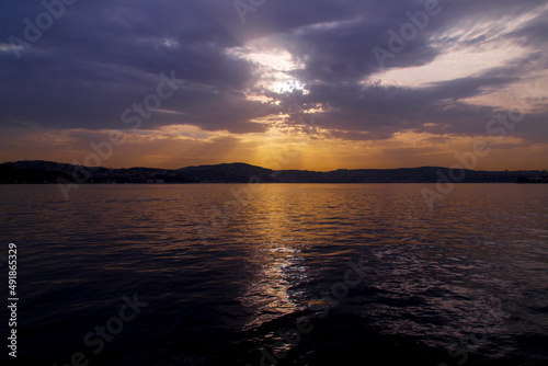 amazing colorful clouds on sunset. Beautiful golden sunset in the sea with saturated sky and clouds. Reflection in the water. Rocky coastal line. Peaceful serene landscape. Nature background.