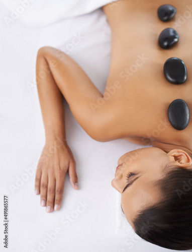 Step one to total relaxation. Shot o a young woman getting a hot rock treatment at a spa.