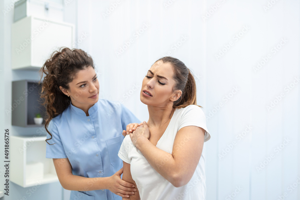 Woman doctor osteopath in medical uniform fixing woman patients shoulder and back joints in manual therapy clinic during visit. Professional osteopath during work with patient concept