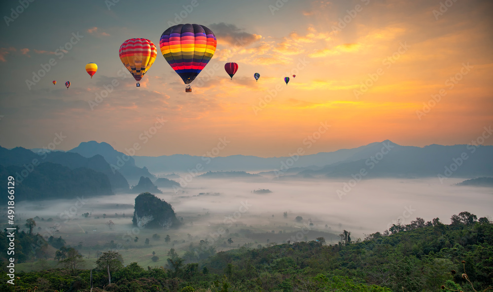Colorful hot air balloons flying over mountain and sea of fog in sunrise. Mountain with hot air balloons on morning.