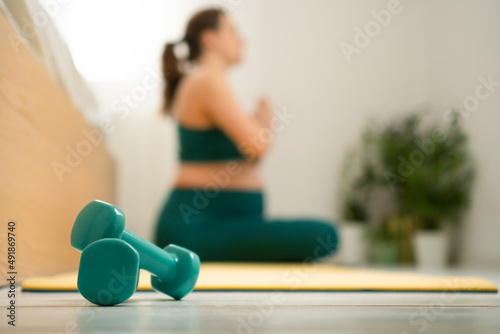 A pregnant woman on background. Concept of a healthy lifestyle during pregnancy. Sports activities before the birth of baby. Useful exercises, fitness for health. Focus on foreground at dumbbells.